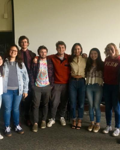 A picture of 9 graduating seniors seniors with their arms around each other, shown from the waist up. 